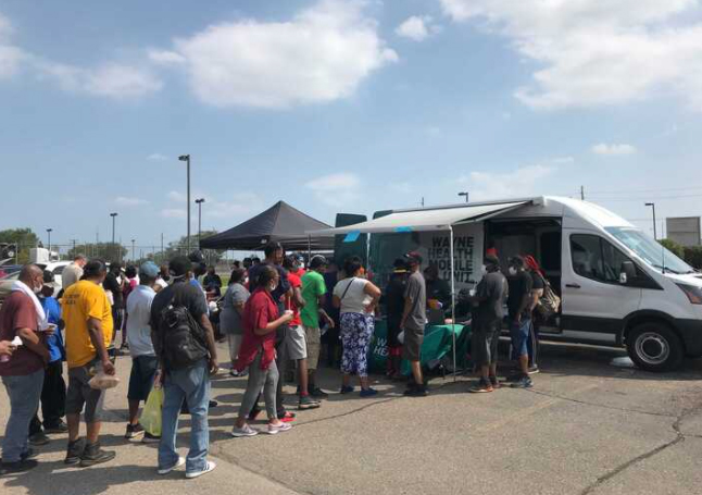 Photo of community members lining up at the Wayne State Mobile Health Unit