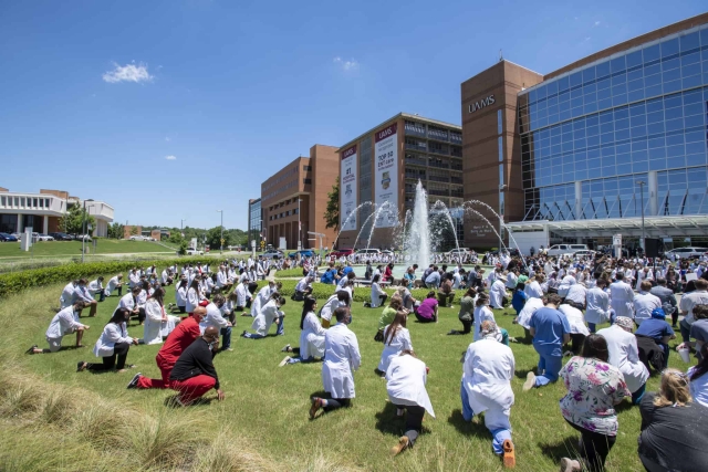 Doctors at UAMS kneeling in front of medical building